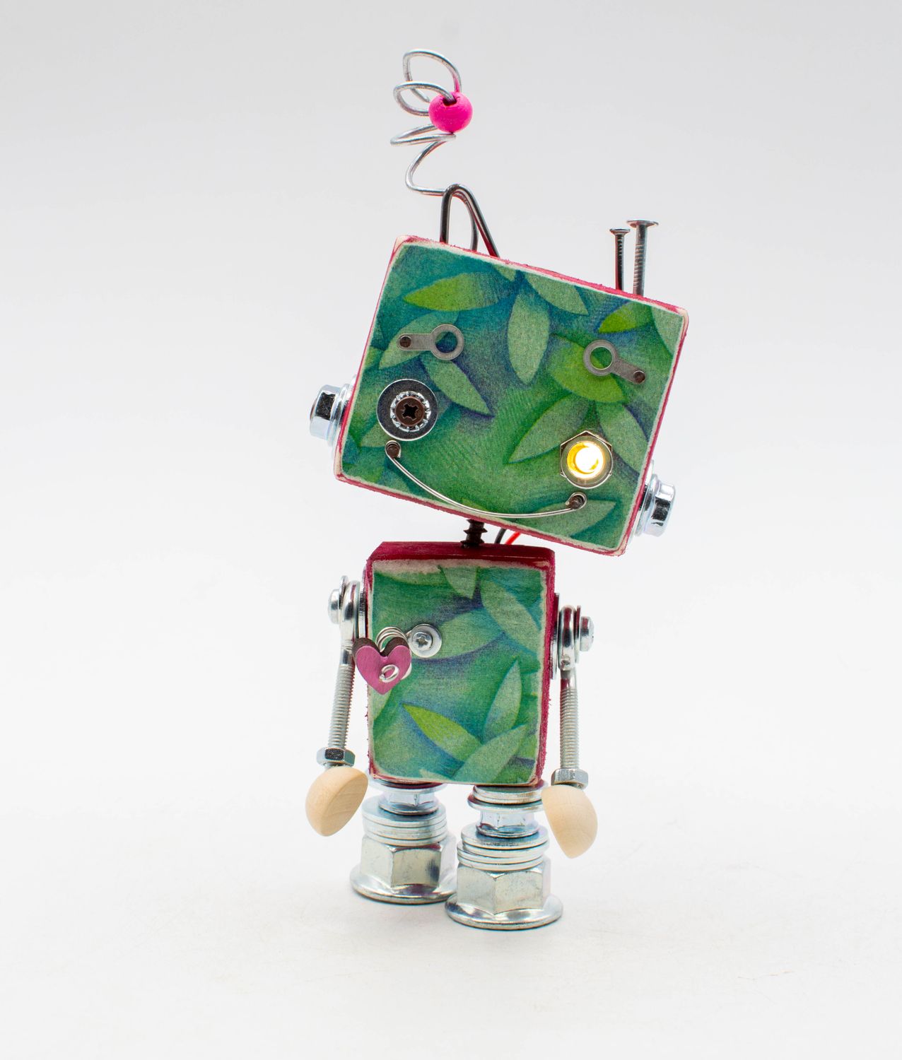 Una figurina robot luci di cortesia in metallo con foglie verdi e cuori rosa decorativi