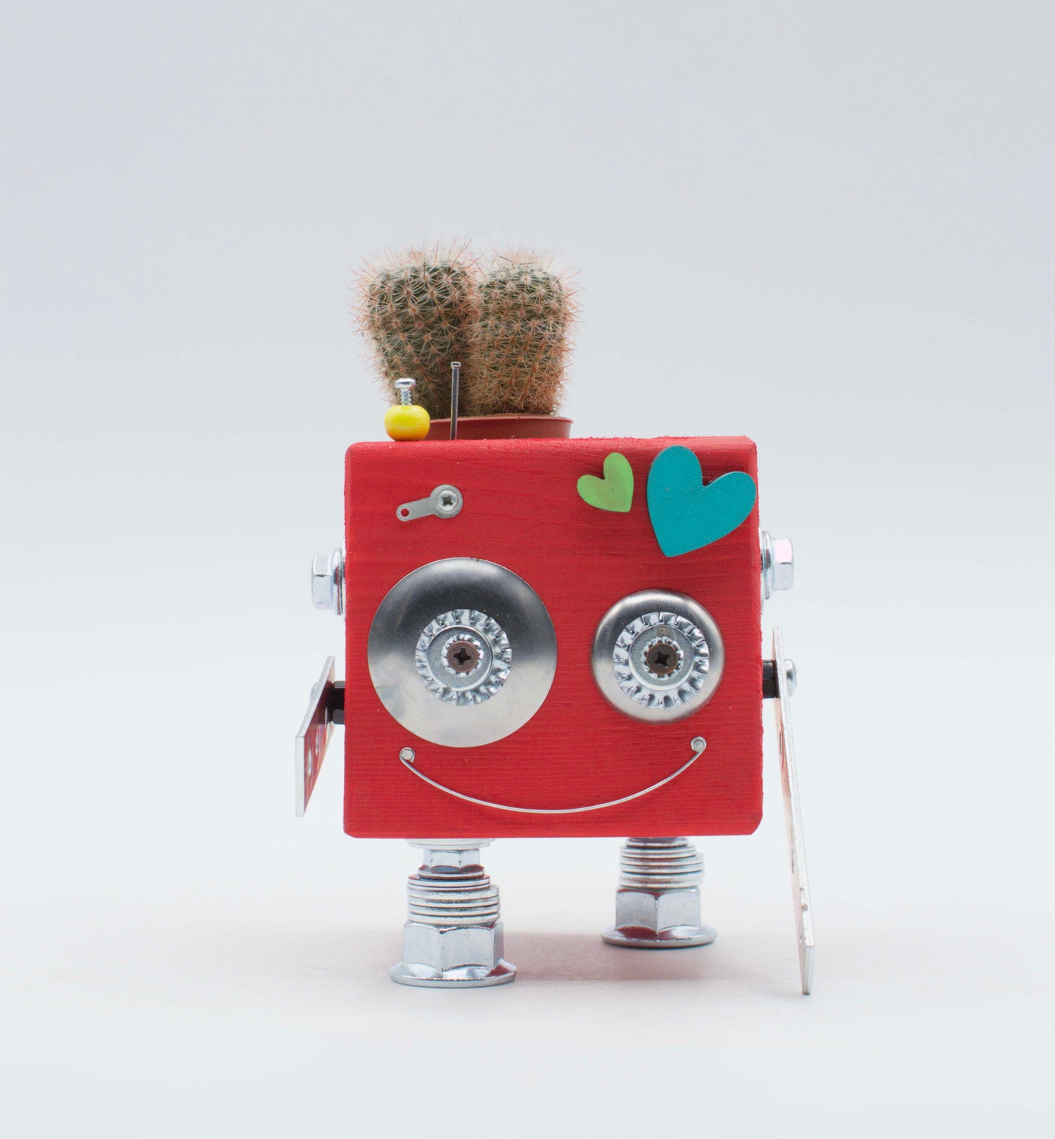 Robot giocattolo porta pianta rosso con occhi e gambe metalliche argento e piccolo cactus sopra