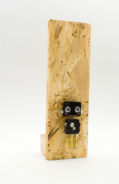 Ciondolo robot in legno tagliato a laser nero con occhi argento e gambe pendenti oro su collana delicata fatta a mano