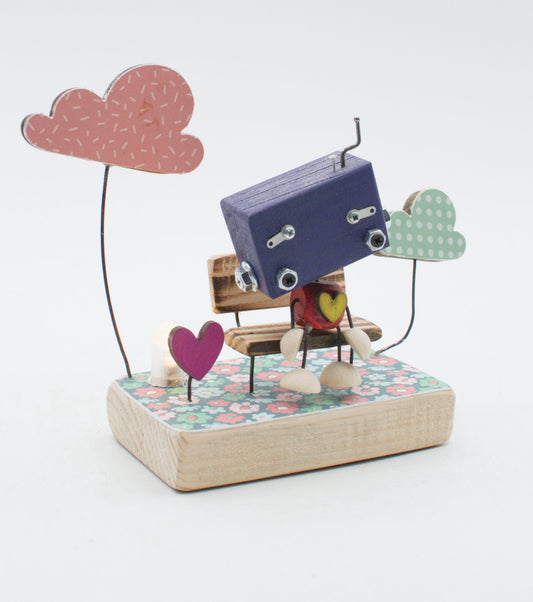 Diorama scultura luminosa stile robot fatto a mano con robot di legno viola e dettagli metallici su panchina miniatura