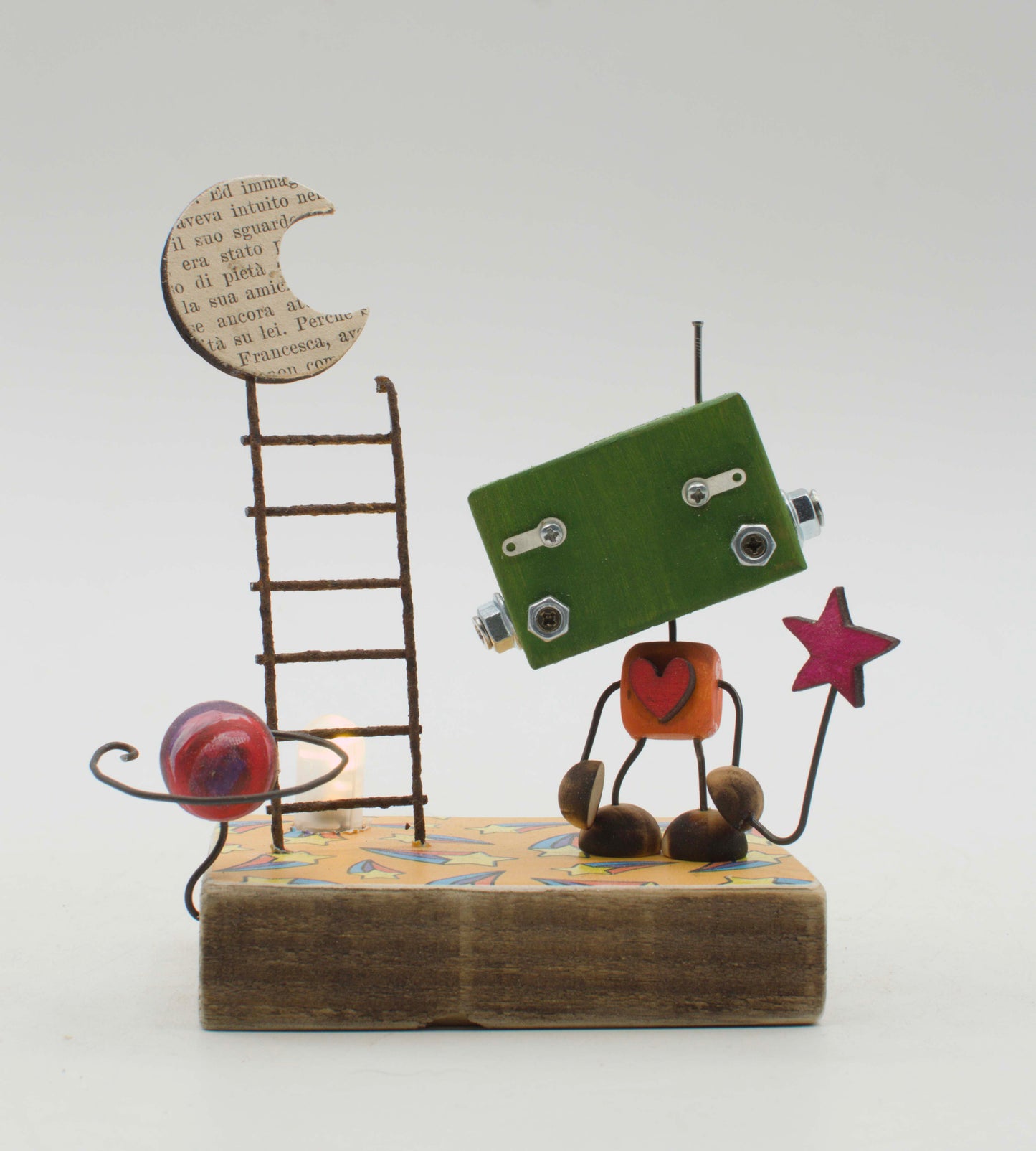 Diorama scultura luminosa stile robot fatto a mano verde con torso arancione a cuore rosso e arti in filo che tiene una stella rosa