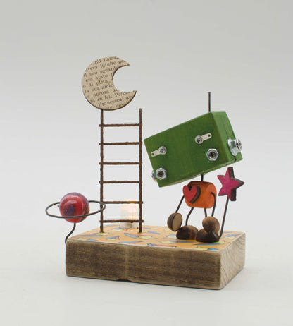Diorama scultura luminosa robot verde con cuore arancione in metallo su base legno con scala e luna di pagine libro