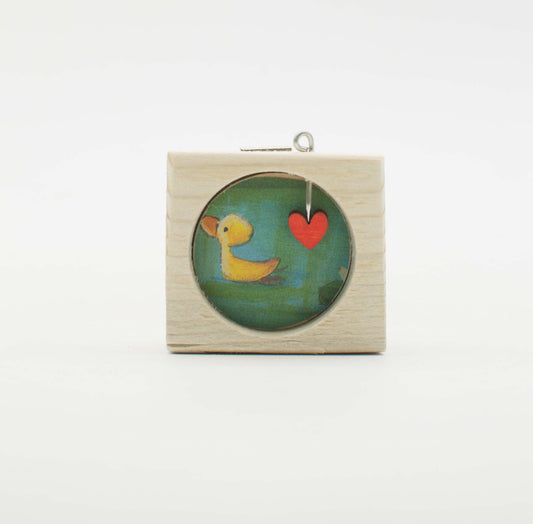 Piccolo quadro artigianale in legno con inserto circolare in vetro raffigurante anatra gialla e cuore rosso su sfondo verde