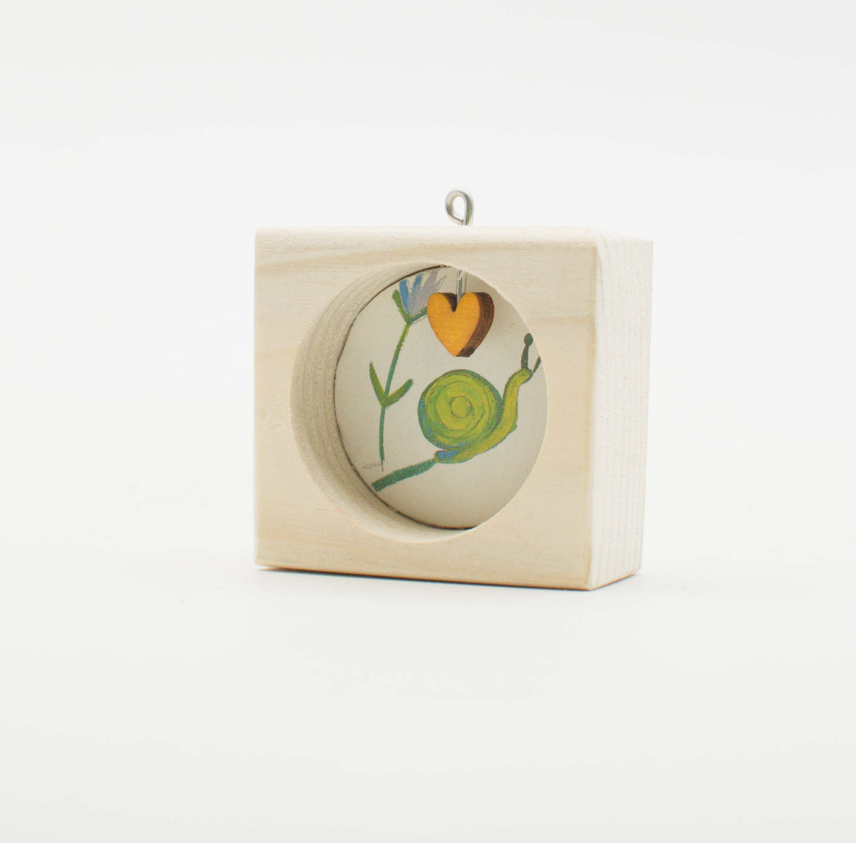 Piccolo quadro artigianale in legno con lumaca verde e cuore arancione su sfondo bianco con appendino argento