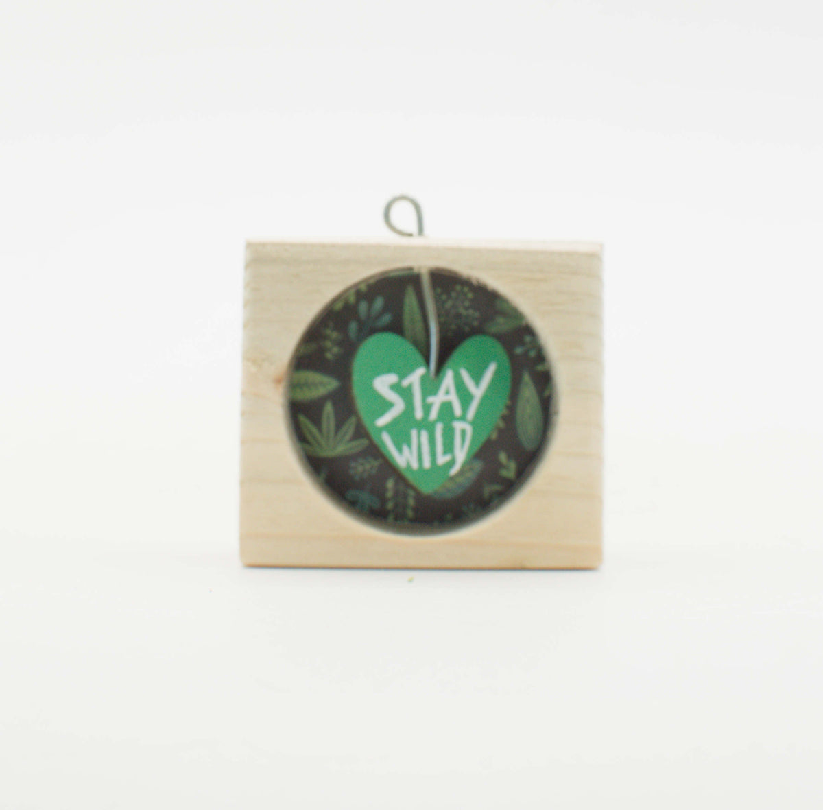 Piccolo quadro artigianale in legno con cuore verde stay wild su sfondo scuro di foglie per appendere