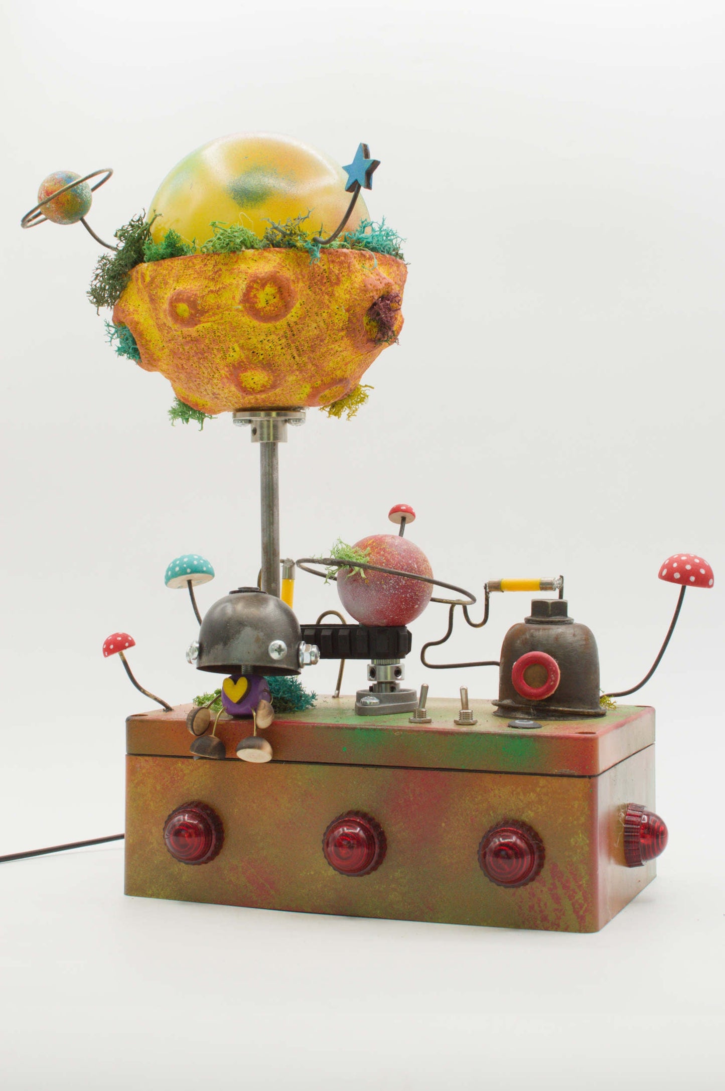 Lampada robot artigianale in metallo riciclato con globo pianeta giallo arancione e base metallica con pulsanti rossi