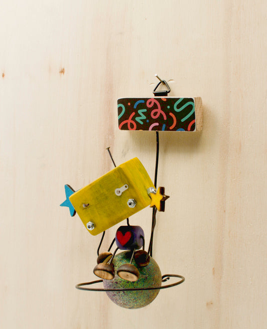 Minibot da appendere scultura robot fatta a mano in legno e metallo con corpo giallo, stelle blu e base pianeta verde
