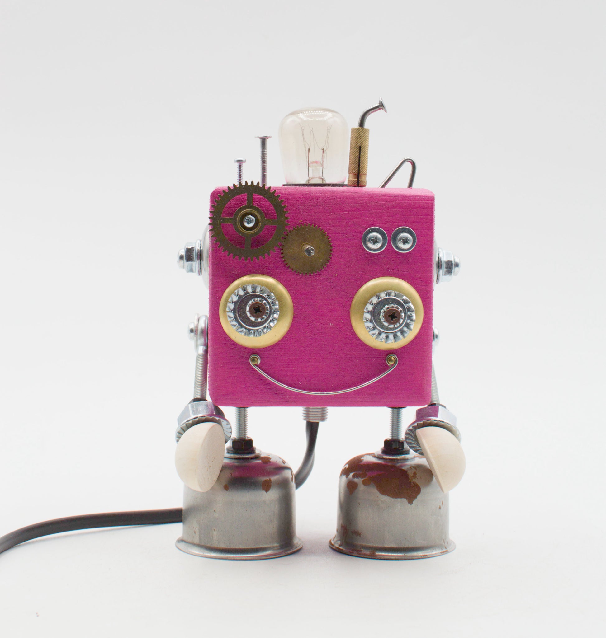 Robot lampada da tavolo cubot rosa in metallo e ingranaggi con occhi bordati oro bocca sorridente e piedi a campana