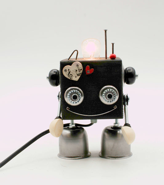 Lampada da tavolo robot cubot nera a forma di cubo con occhi argentati a cerchio, cuori decorativi e piedi a forma di campana