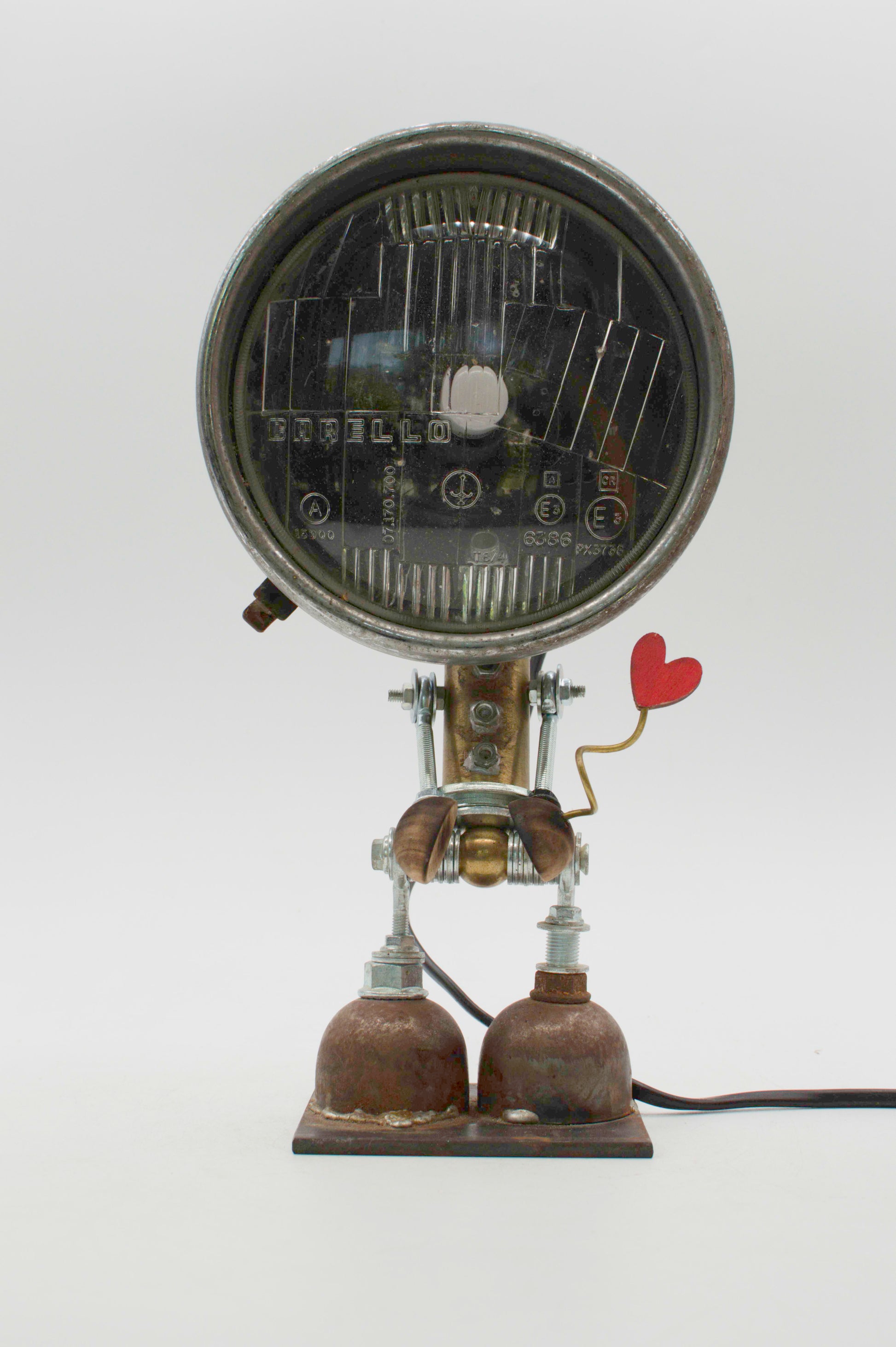 Robot lampada da tavolo stile fanale con testa circolare nera e cuore rosso su braccio metallico riciclato