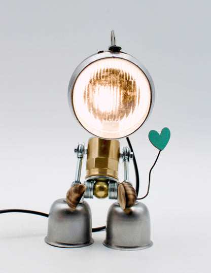 Lampada da tavolo robot steampunk in ottone e cromo con testa circolare e braccia articolate che tengono un cuore verde