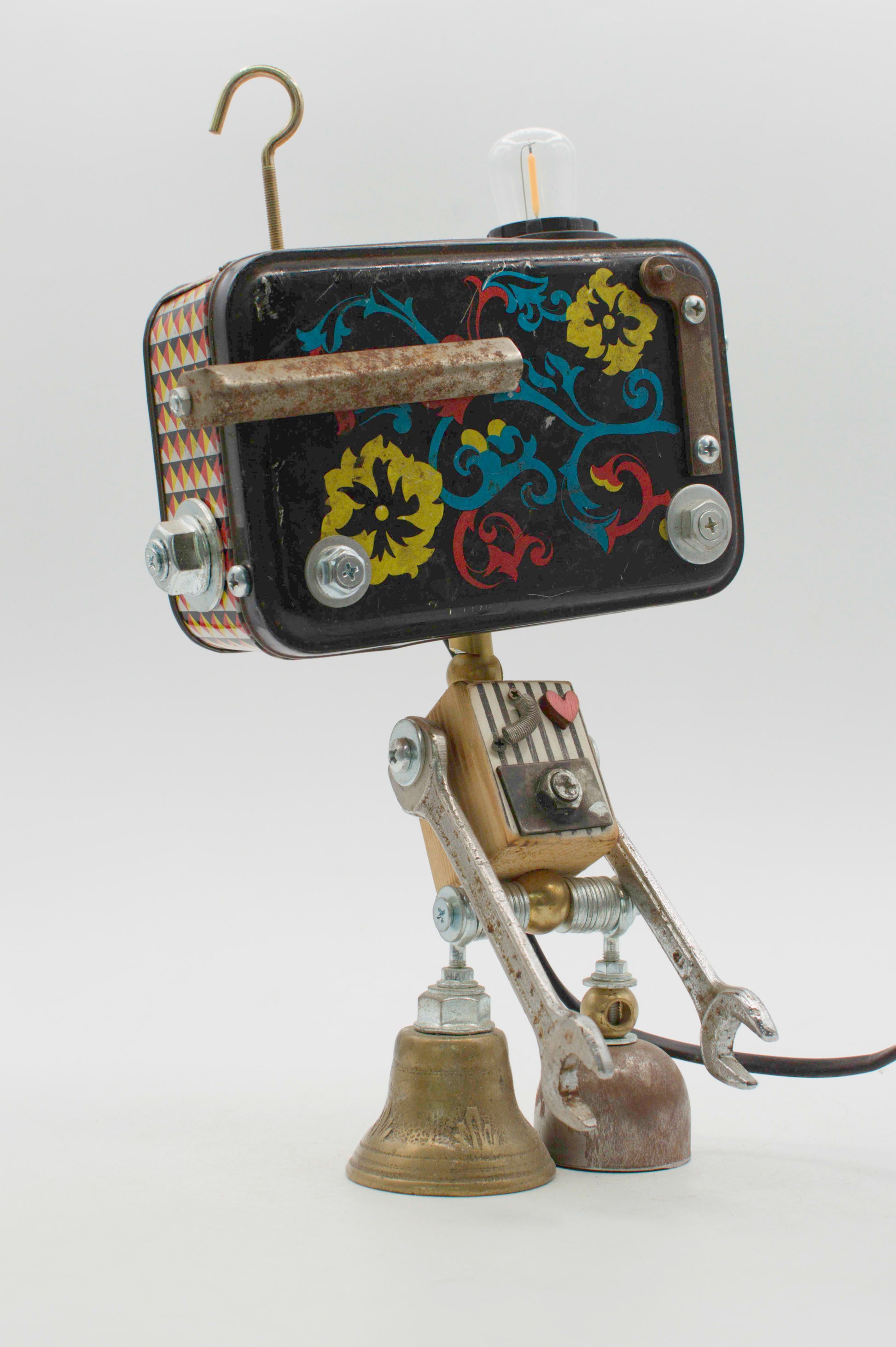 Robot lampada da tavolo stile fantasy con testa rettangolare nera a fiori e arti meccanici in ottone e argento
