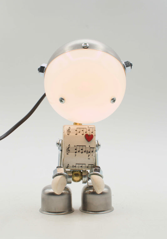 Lampada da tavolo robot kodama fatta a mano in metallo con testa luminosa circolare e corpo di spartiti musicali con cuore rosso