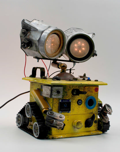 Graziosa lampada creata a mano stile wall e con robot giallo e occhi arancioni luminosi su cingoli tank
