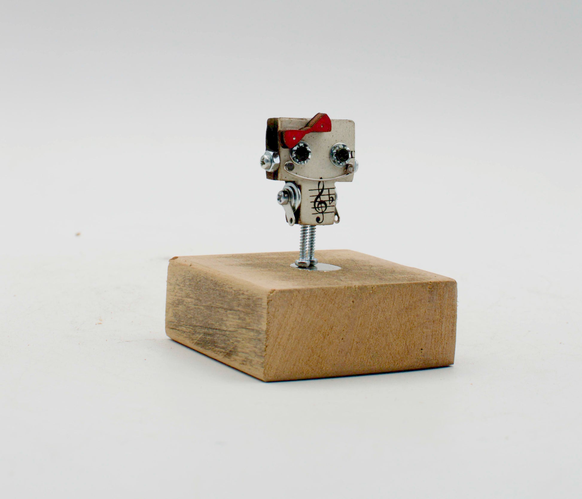 Spilla robot in legno tagliato a laser con corpo metallico argento, occhi neri e fiocco rosso, fatta a mano