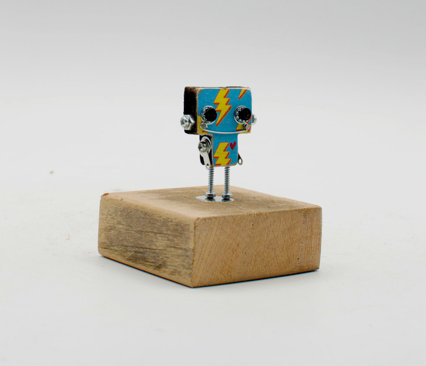 Spilla robot in legno tagliato a laser con testa quadrata blu e fulmini gialli su base di legno rustica fatta a mano