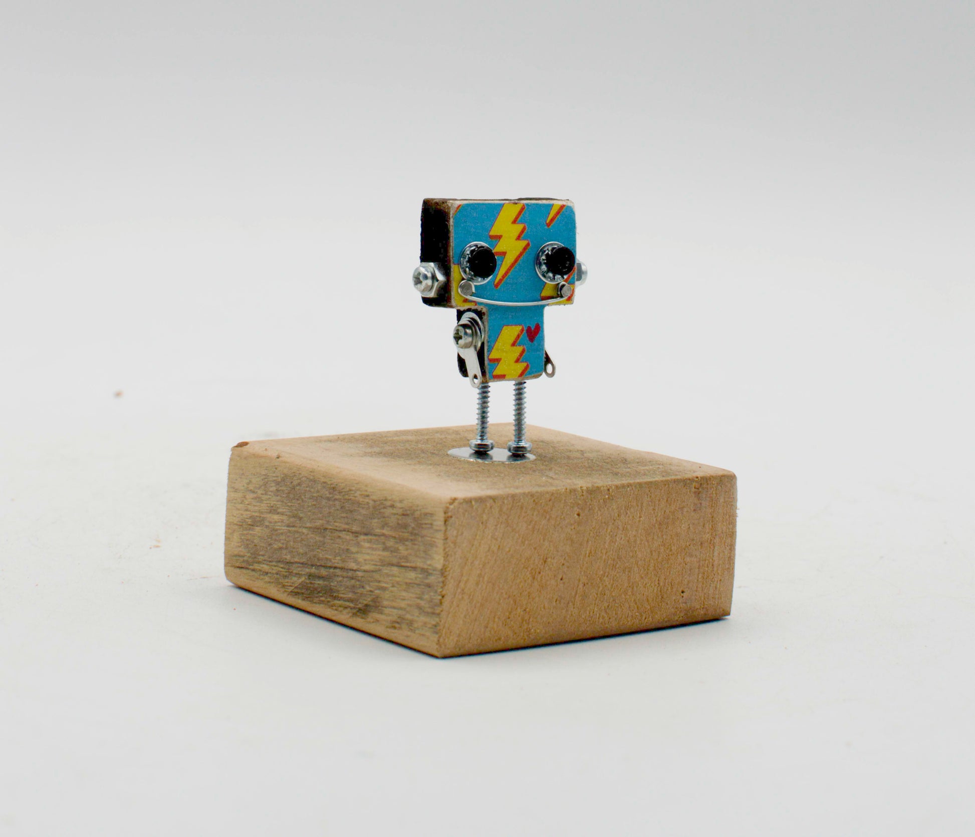 Spilla robot in legno tagliato a laser con testa quadrata blu e fulmini gialli su base di legno rustica fatta a mano