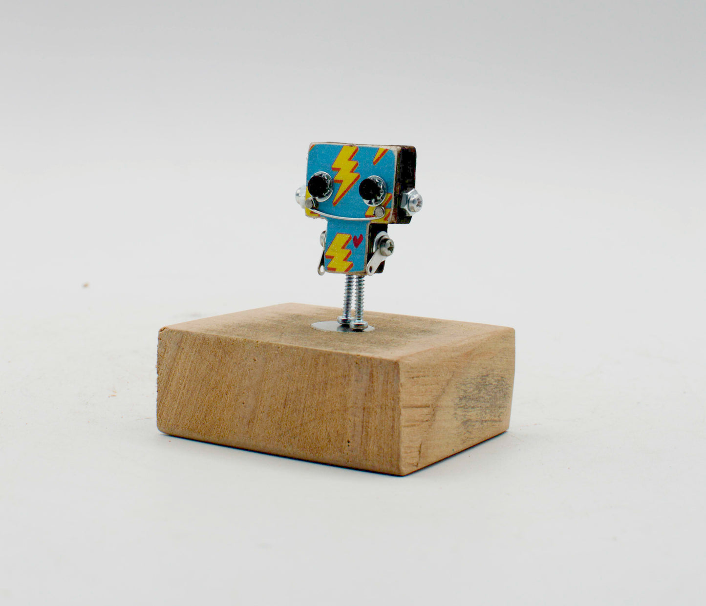 Spilla robot in legno tagliato a laser con corpo blu e fulmini gialli su base in legno rustico fatta a mano