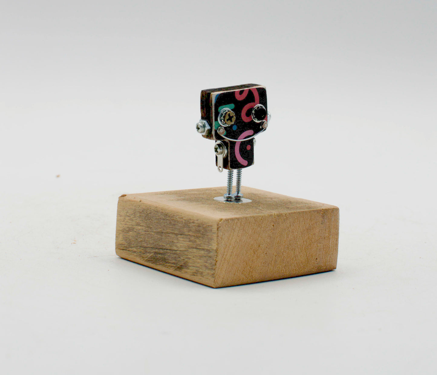Spilla robot in legno tagliato a laser con testa nera a spirale rosa e gambe a vite su base di legno rustico fatta a mano