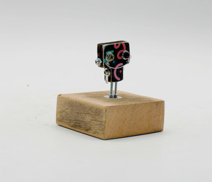 Spilla robot in legno tagliato a laser con testa nera a spirale rosa e gambe a vite su base di legno rustico fatta a mano