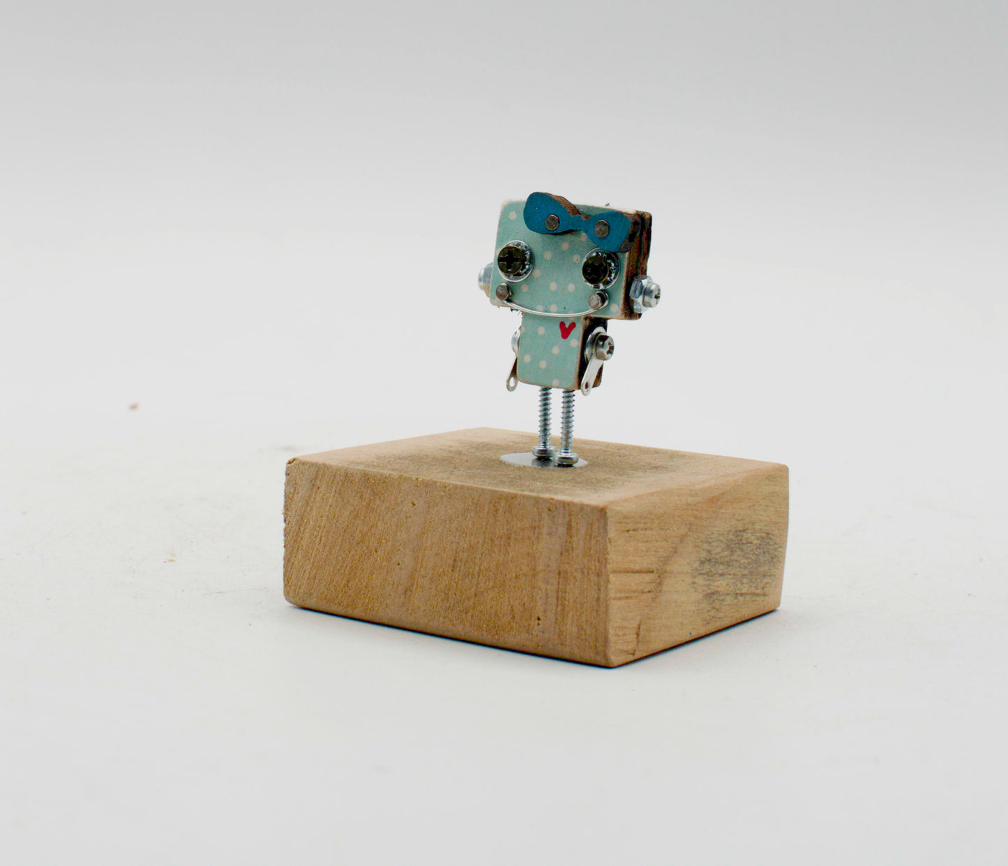 Spilla robot in legno tagliato a laser con corpo azzurro a pois, occhi neri e gambe a vite metalliche, fatta a mano