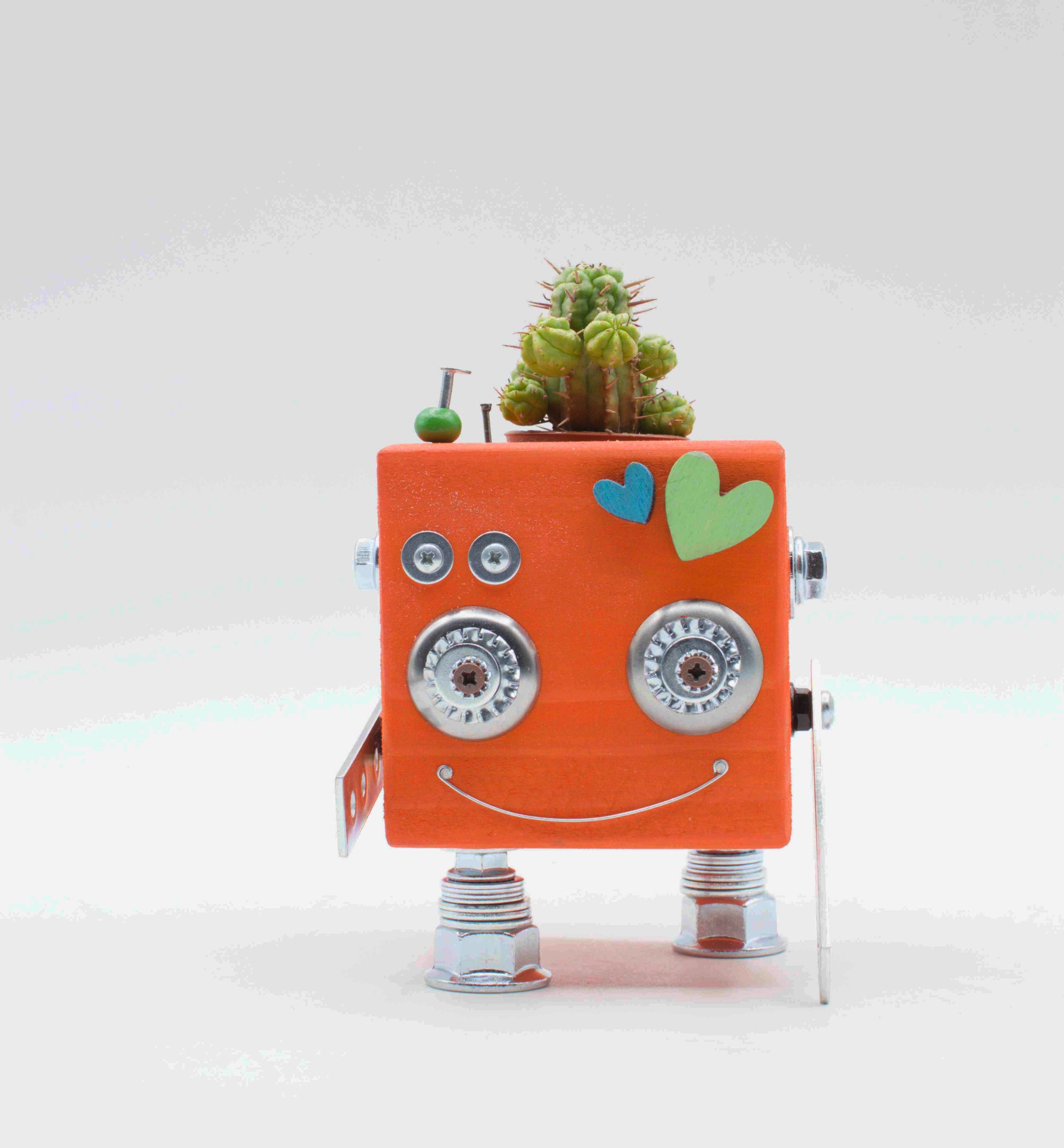 Vaso a forma di robot in legno fatto a mano color pesca con occhi e piedi metallici e piccolo cactus sul lato superiore